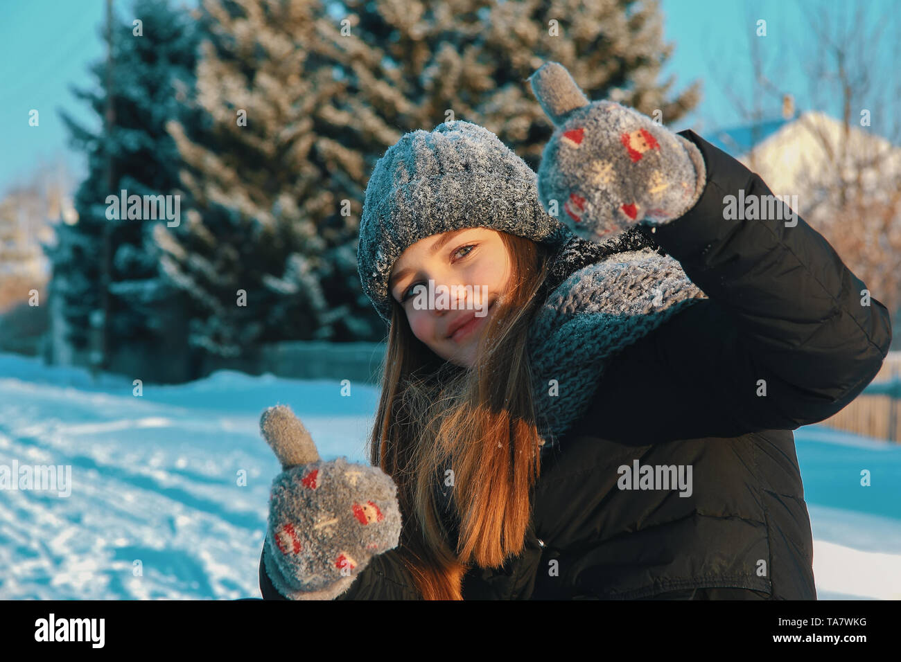 Schöne kaukasische Mädchen mit losen Haare in einem gestrickte Mütze, Schal und Handschuhe draußen im Dorf auf einem Winter nachmittag Nachmittag zeigt gute Laune ein Stockfoto