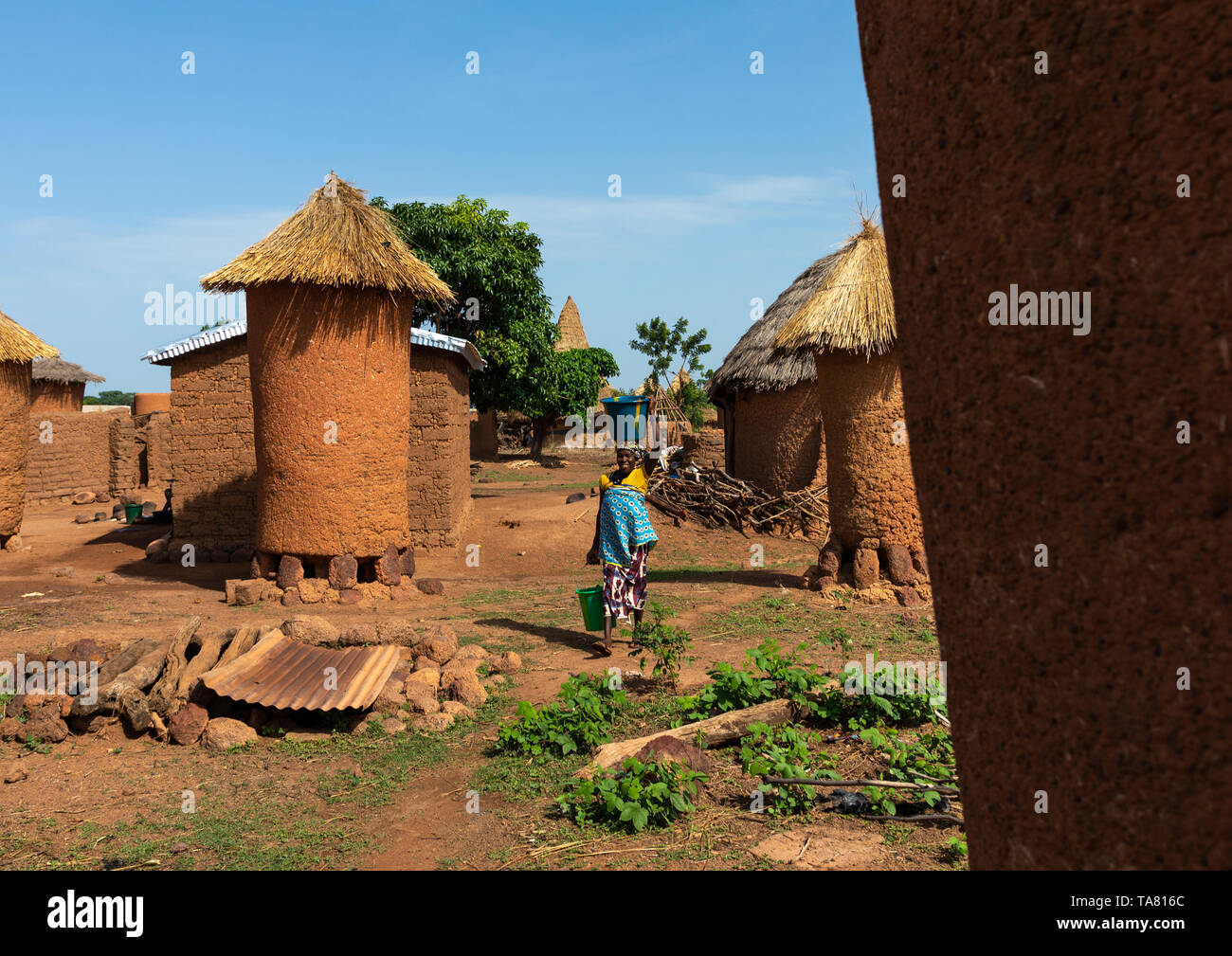 Senufo Frau, die Wasser vorbei vor Getreidespeicher, Savanes Bezirk, Niofoin, Elfenbeinküste Stockfoto
