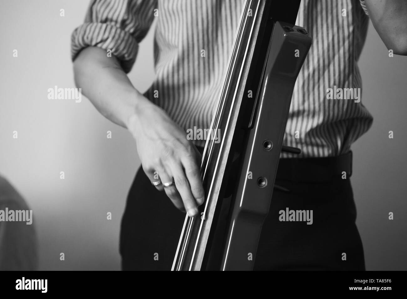 Mann spielt moderne elektrische Kontrabass in der musikalischen Studio, Schwarze und Weiße stilisierte Foto Stockfoto