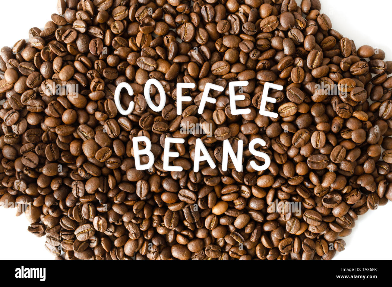 Kaffeebohnen auf weißem Hintergrund mit weißer Schrift in der Mitte. Stockfoto