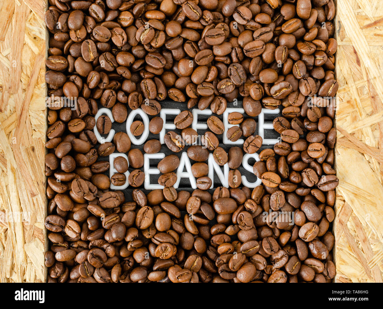 Hintergrund mit Kaffeebohnen mit weißer Schrift in der Mitte. Stockfoto