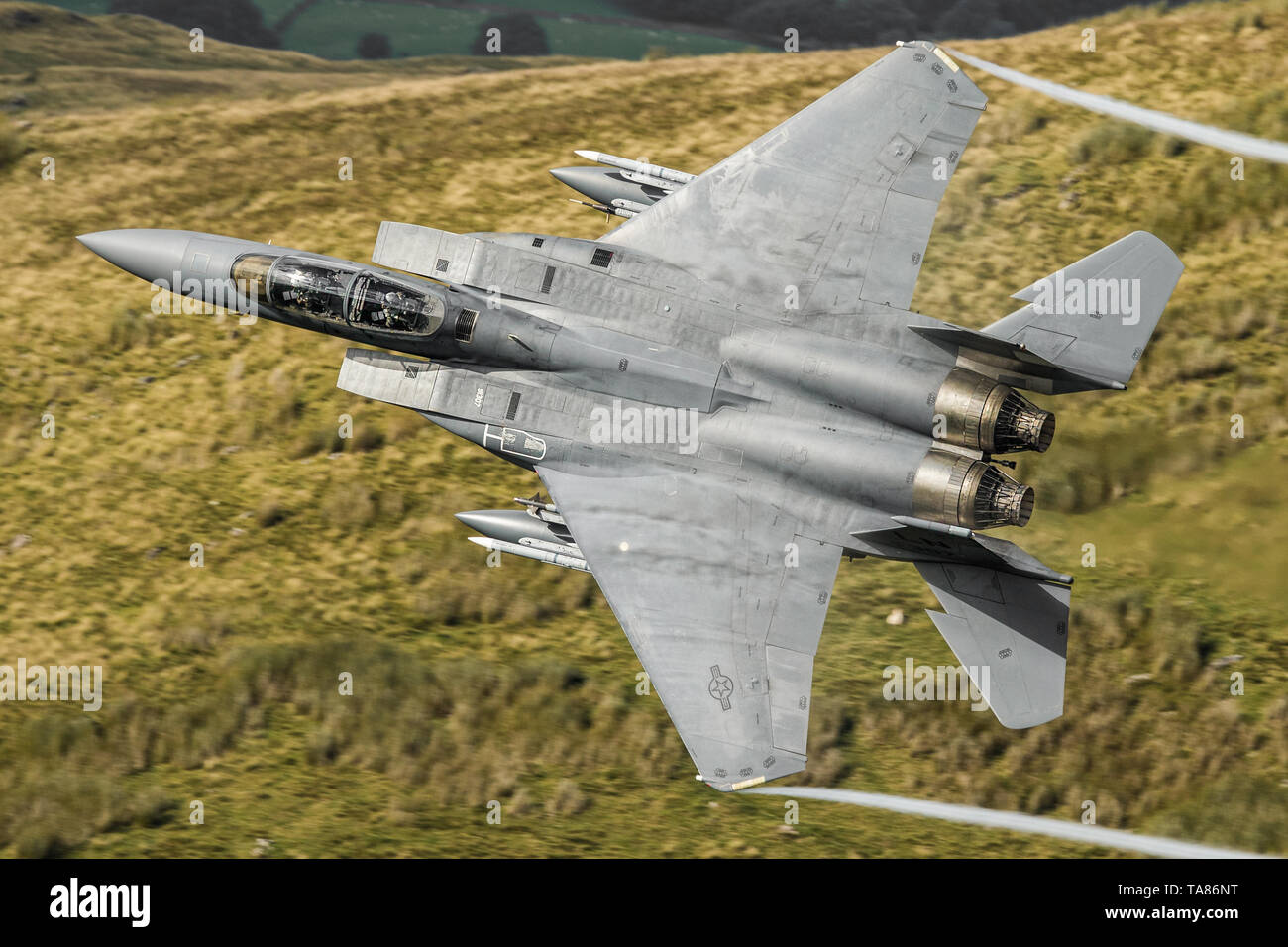 USAF F-15 E Strike Eagle flying low level durch das Mach Loop in Wales, Großbritannien Stockfoto