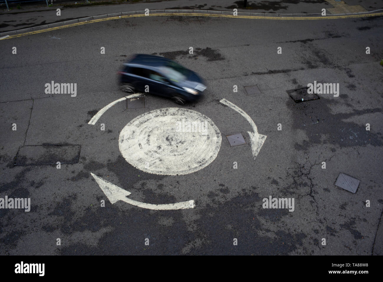 Luftaufnahme von einem lackierten Pfeil Kreisverkehr mit einem einzigen Auto herum zu gehen. Könnte als eine Analogie oder Konzept als verloren oder Going In Circles verwendet werden. Stockfoto