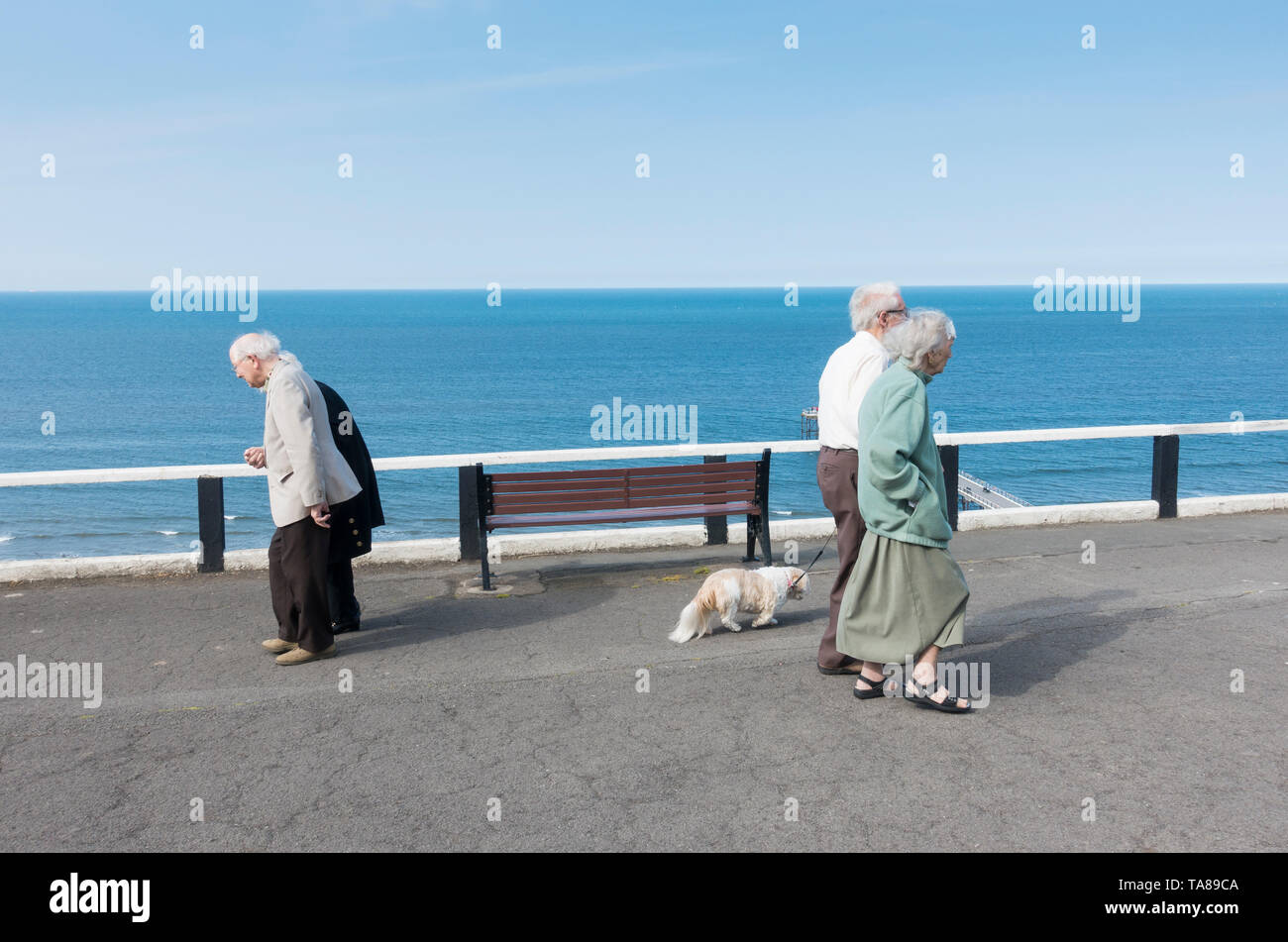 Ältere Paare zu Fuß entlang der Promenade mit Blick auf das Meer. Großbritannien Stockfoto