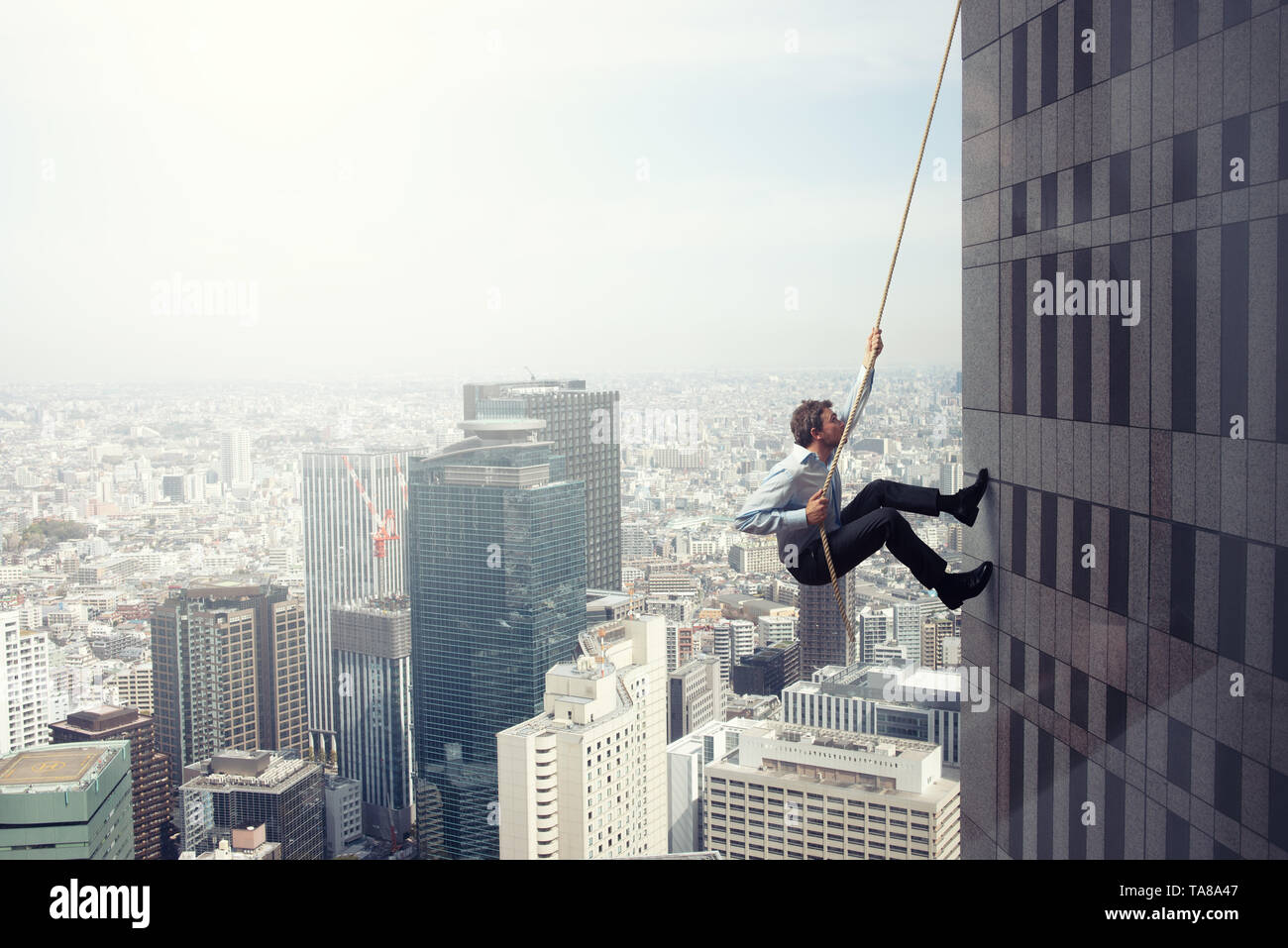 Geschäftsmann klettert ein Gebäude mit einem Seil. Konzept der Bestimmung Stockfoto