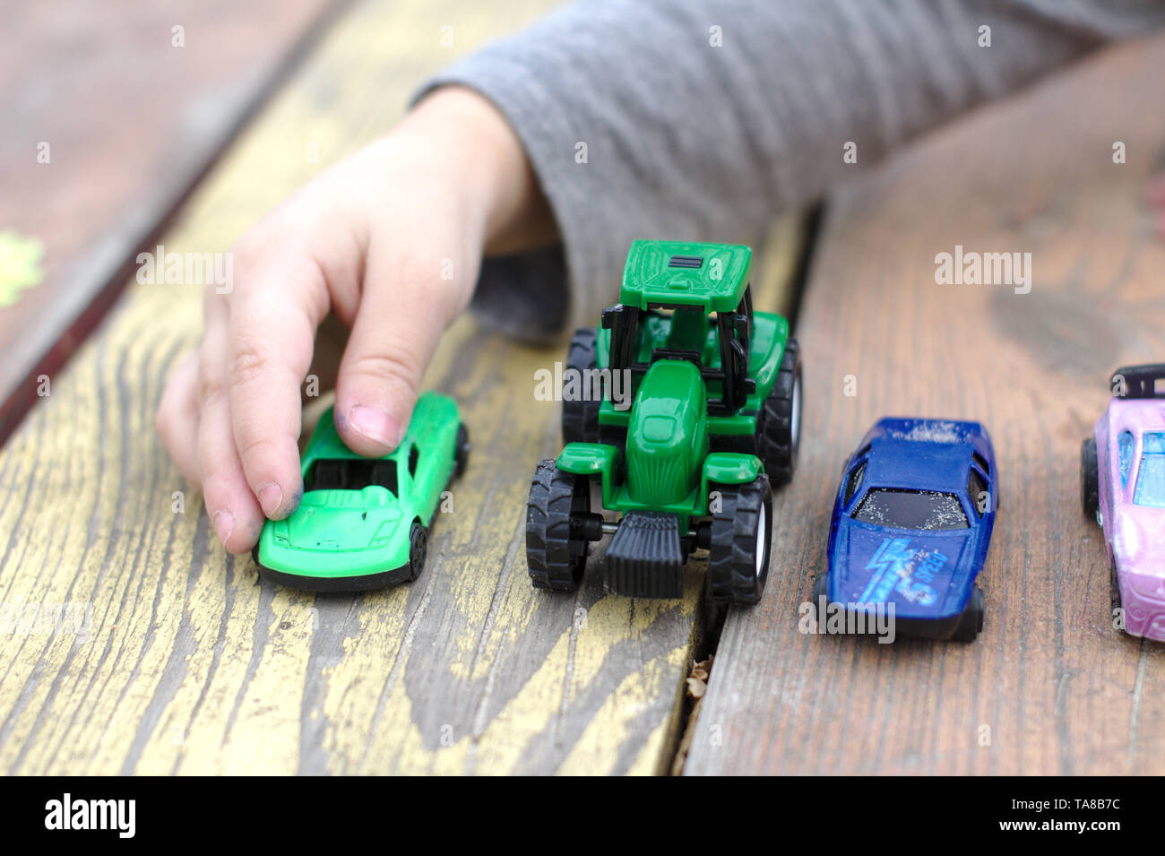 Eine kleine Kinder Hand weist auf ein Spielzeug Auto unter einer Vielzahl  von Autos auf einer hölzernen rot-gelb Tabelle Stockfotografie - Alamy