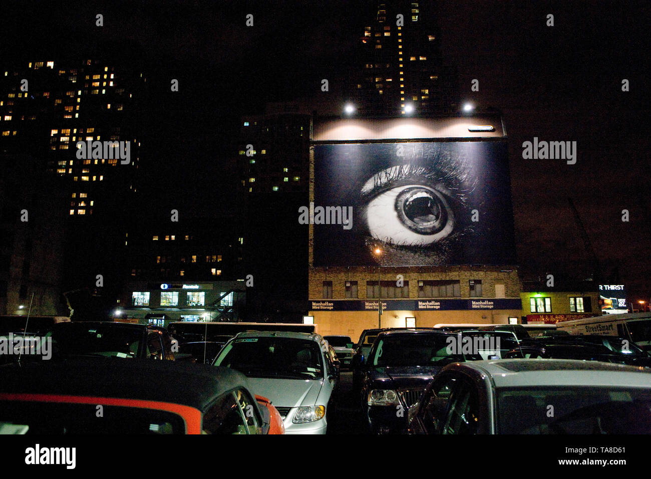 Parkplatz im Freien mit einem großen Plakat und das Stadtbild im Hintergrund bei Nacht, Midtown Manhattan, New York City, New York, USA Stockfoto