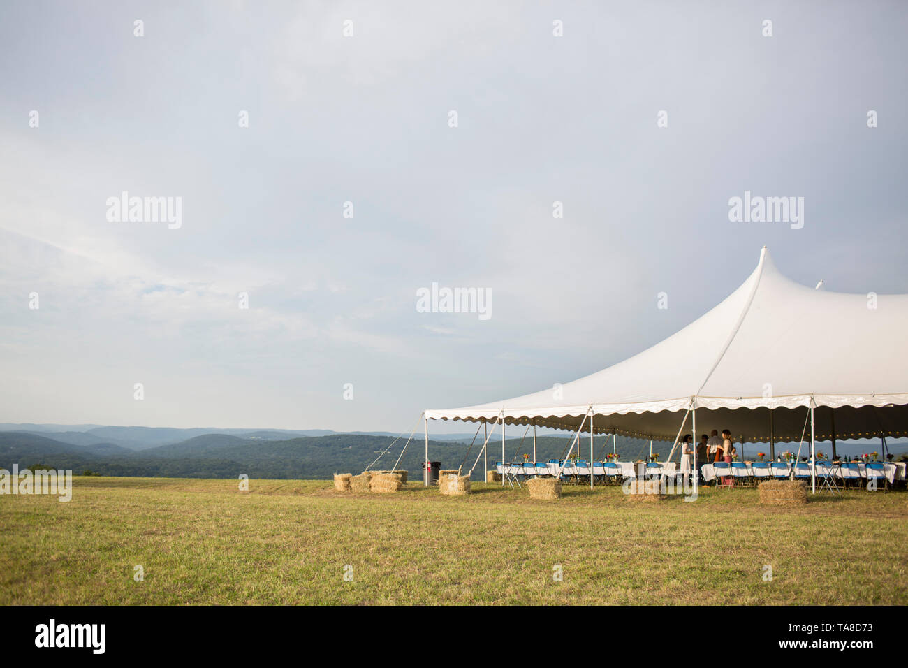 Gruppe von Personen bei Outdoor Party im großen Zelt auf hohen Hügel mit sanften Hügeln im Hintergrund Stockfoto