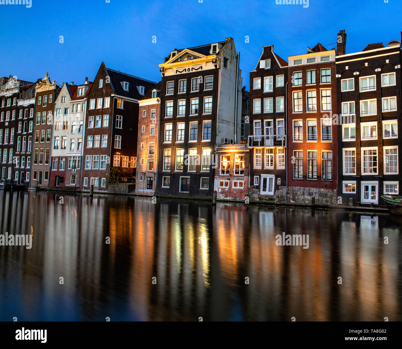 Damrak Grachtenhäuser bei Nacht - Amsterdam Canal House Reflexion tanzen Häuser von Damrak Reflexionen in der Nacht - reflektierende Häuser canal Damrak. Stockfoto