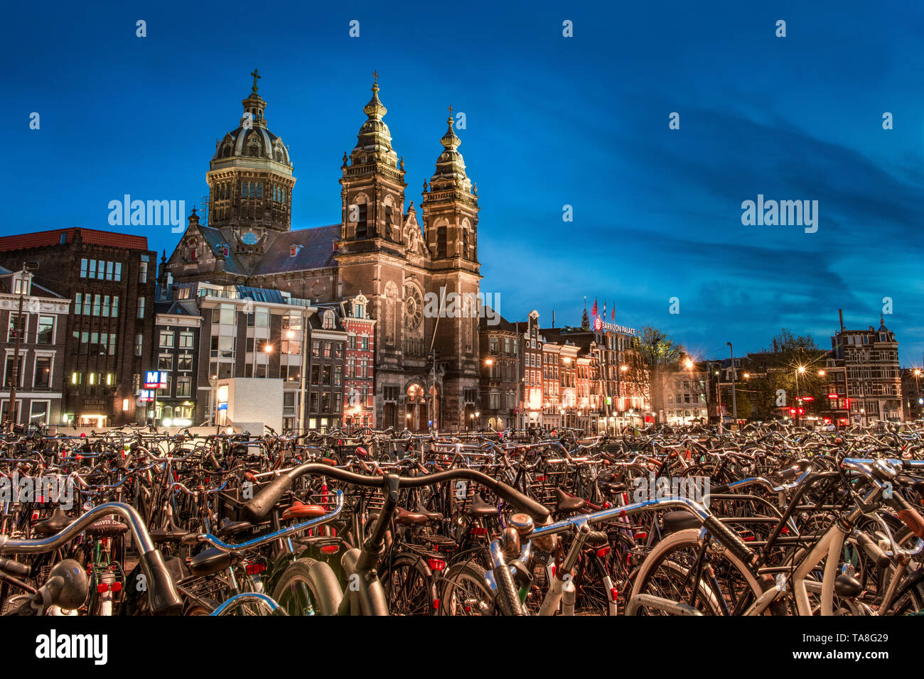 Amsterdam Fahrräder - Fahrräder in Amsterdam bei Nacht mit der Kirche des Heiligen Nikolaus im Hintergrund - Hunderte von abgestellte Fahrräder - biketown Amsterdam Stockfoto