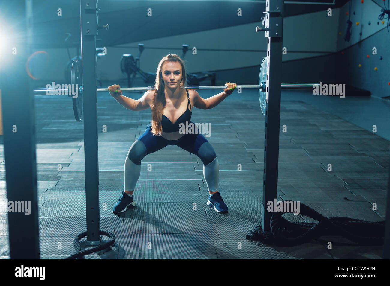 Gymnast Mädchen tun Hocke barbell. Vorderansicht der attraktive junge Frau Stockfoto