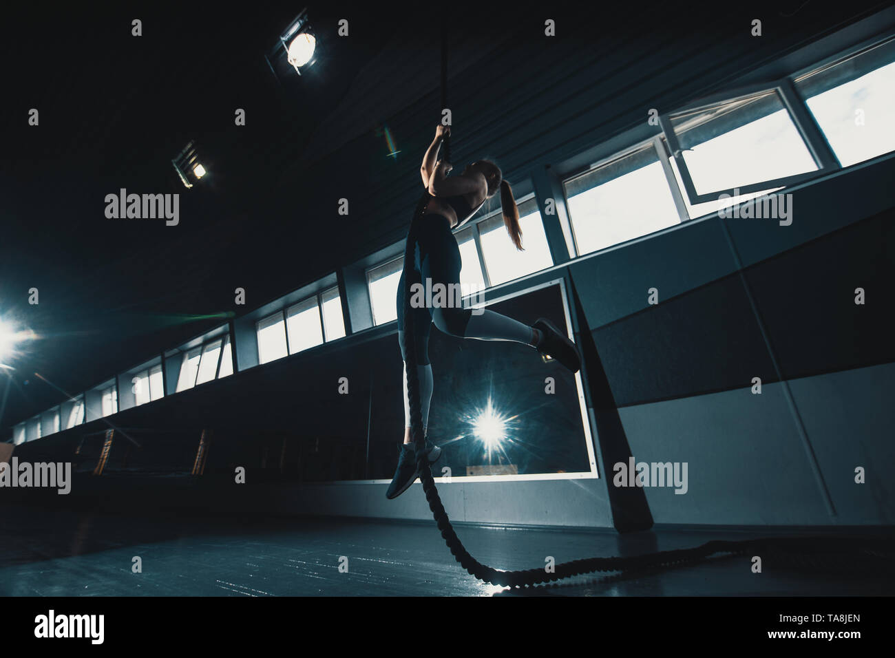 Volle Länge Breite winkel Schoß einer Frau, die das Seil an der Turnhalle klettert. Copyspace Hintergrund mit Leichtathletik gesunde Zusammensetzung. Crossfit und Fitne Stockfoto
