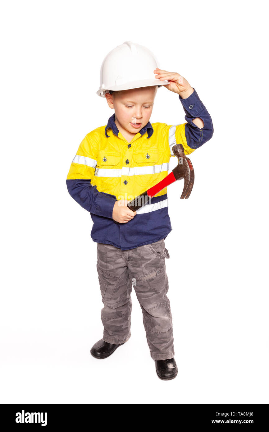 Junge blonde kaukasischen jungen Rolle spielen als Bauarbeiter in einem gelben und blauen Hi-viz Shirt, Stiefel, weißen harten Hut, ein roter Hammer ohne Band mich Stockfoto