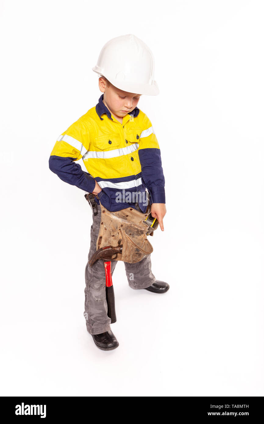 Junge blonde caucasian Boy nach unten mit einem grimmigen Blick Rolle spielen als Bauarbeiter Supervisor in einem gelben und blauen Hi-viz Shirt, Stiefel, Stockfoto