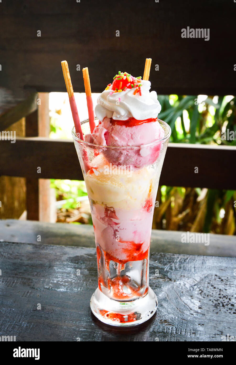Eis in ein Glas/Vanille- und Erdbeereis mit cracker Sticks im Glas auf dem Tisch rustikal Holz Hintergrund Stockfotografie