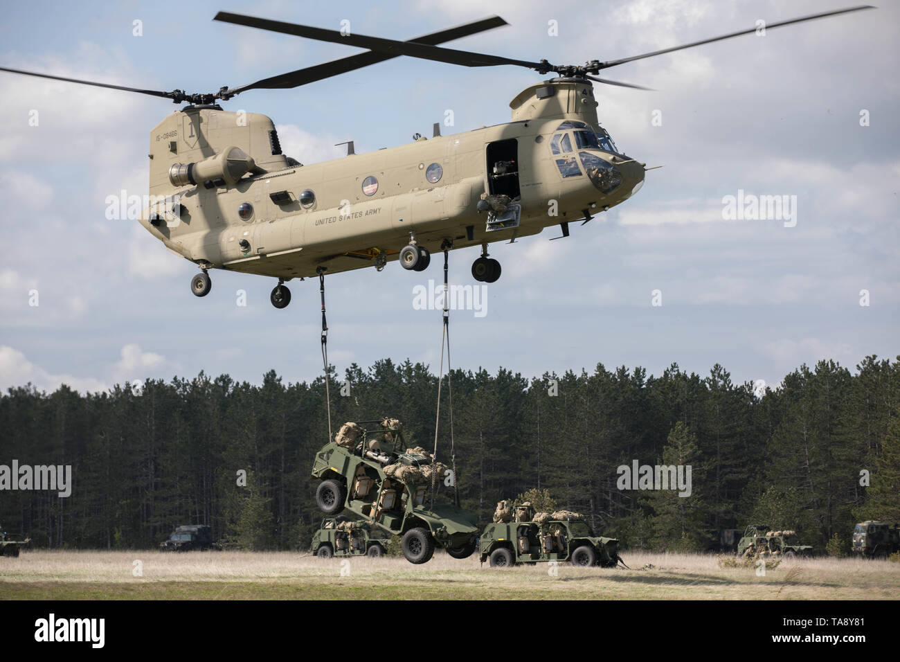 Ein U.S. Army CH-47 Chinook Hubschrauber, Bravo Company, 2.BATAILLON, 1 Combat Aviation Brigade, 1 Infanterie Division, führt eine Schlinge Ladevorgang bis zu wählen Sie eine Armee Boden Mobilität Fahrzeug (AGMV) mit Fallschirmjägern in Angriff zu Unternehmen, 1.BATAILLON, 503Rd Infanterie Regiment, 173Rd Airborne Brigade, Zugewiesen an Bord während der Übung sofortige Reaktion bei Vojarna Josip Jovic Airbase, Udbina, Kroatien, 17. Mai 2019 geladen. Übung sofortige Reaktion ist eine multinationale Übung von kroatischen Streitkräften geführt, der slowenischen Streitkräfte, und die US-Army in Europa. Die Logistik - fokussierte exerci Stockfoto