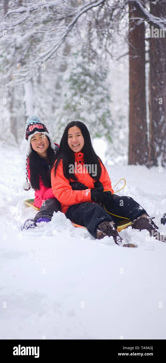 Zwei Mädchen sitzen auf einem snowsled im Schnee bei Big Bear Mountain. Stockfoto