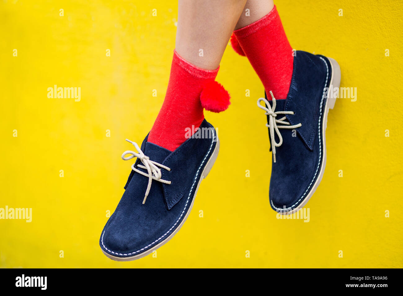 Blau Wildleder Stiefel mit roten Socken gegen eine gelbe Wand. Schrullig und hellen Fashion Concept Stockfoto