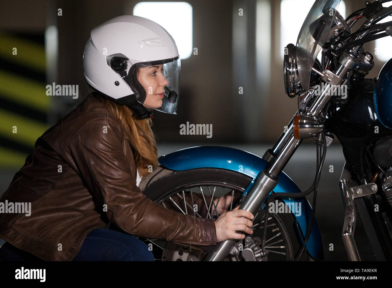 Frau biker Suchen in Scheinwerfer von Motorrad- und halten sich an den Händen rad, u-garrage Stockfoto
