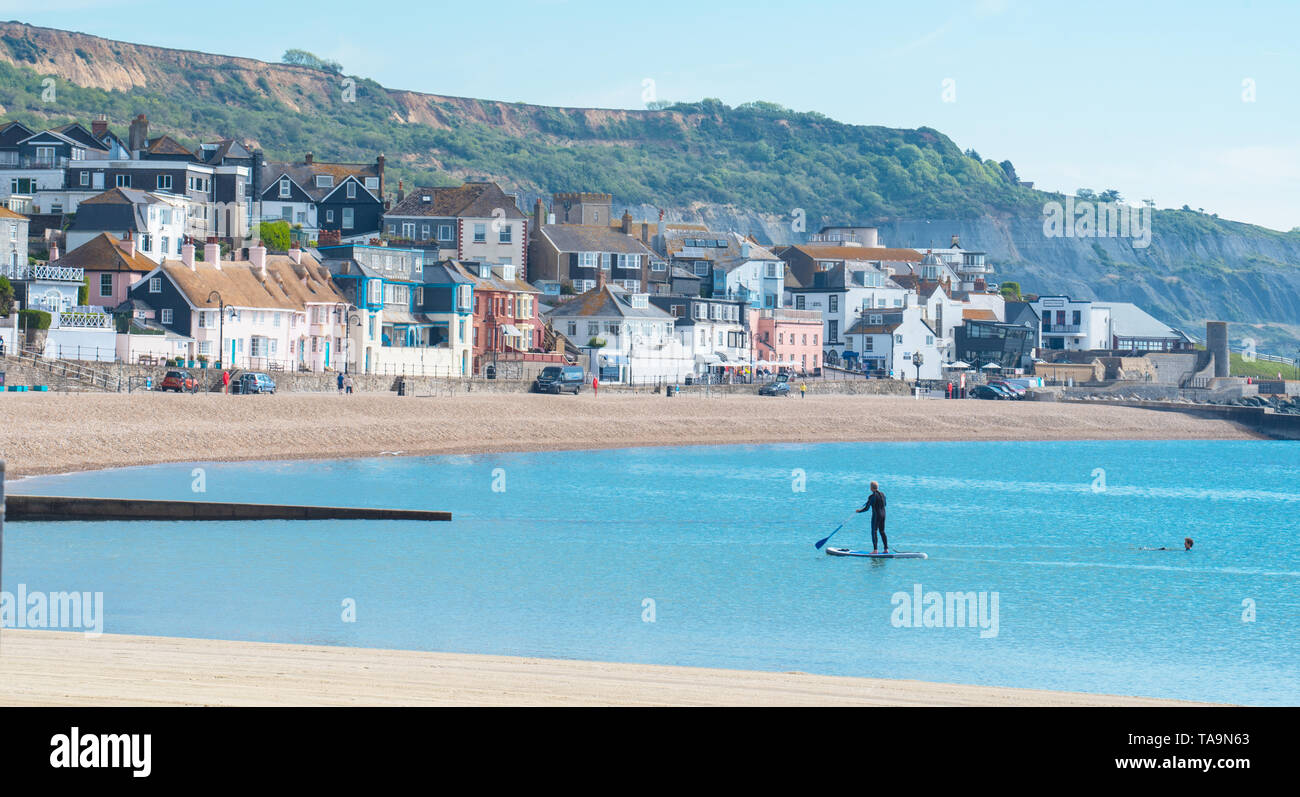 Lyme Regis, Dorset, Großbritannien. 23. Mai 2019. UK Wetter: Ein herrlicher Morgen am malerischen Strand in der Küstenstadt Lyme Regis. Das beliebte Resort liegt ruhig und still heute vor der bevorstehenden May Bank Holiday. Ein einsamer Paddel boarder nutzt die Vorteile der friedlichen Bedingungen. Massen sind in Scharen zum beliebten Strand nächste Woche erwartet in der lauen Wetter, die über der Südküste von England Prognose wurde zu sonnen. Credit: Celia McMahon/Alamy Leben Nachrichten. Stockfoto