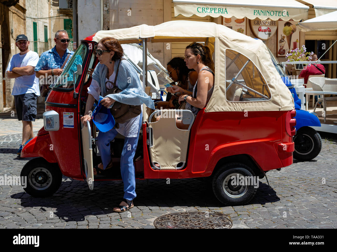 Ostuni, Italien, 24. Juni 2018: Touristen in der charakteristischen Straßen der Altstadt von Ostuni. Einige verwenden spezielle 3-rädrigen Motorrädern zu r Stockfoto