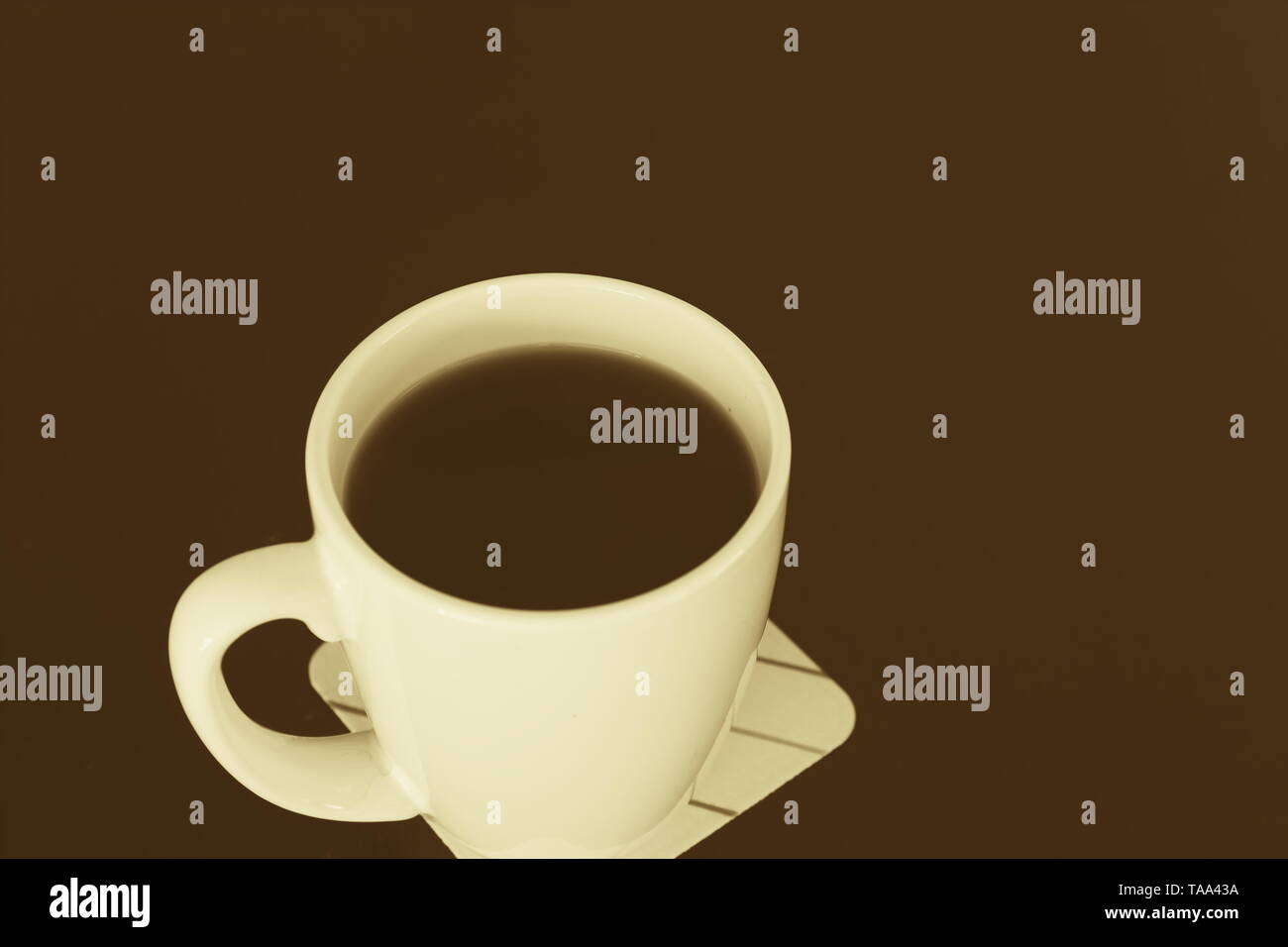 Tasse Kaffee auf eine dunkle Oberfläche split getönten in Gelb und Braun Stockfoto