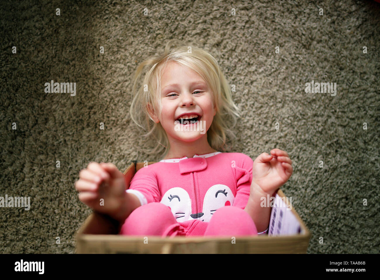 Ein fröhlicher kleiner 3 Jahr alten Kind in ihrem Pyjama, lacht, als sie in einem Karton in Ihrem Haus spielt. Stockfoto