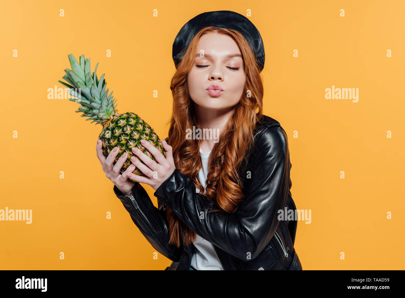 Schöne rothaarige Mädchen in Lederjacke mit Ananas und schmollend Lippen  isoliert auf Gelb Stockfotografie - Alamy