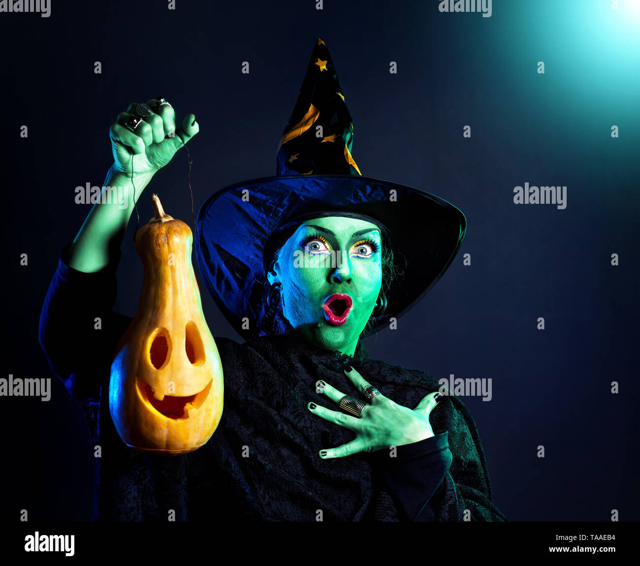 Hexe mit grüner Haut Holding geschnitzten Halloween Kürbis Laterne an dunklen Hintergrund Stockfoto