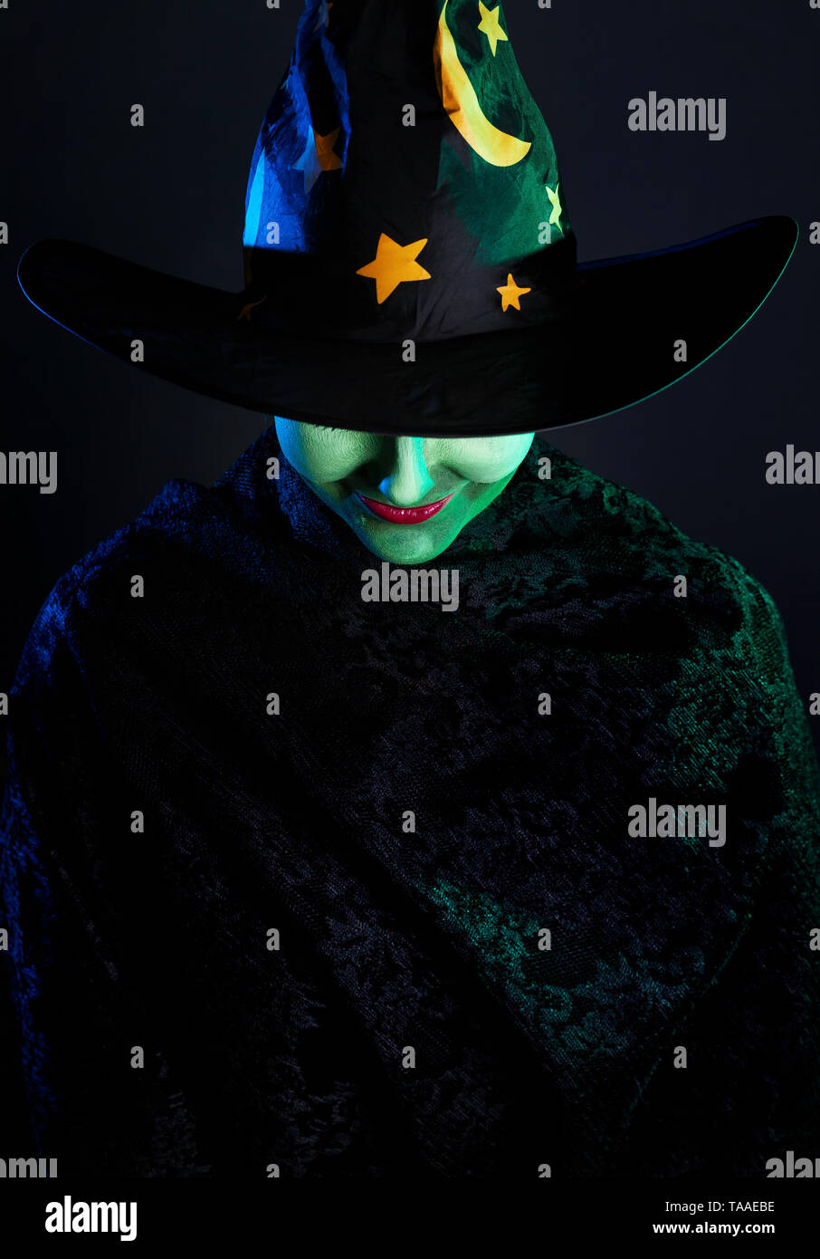 Hexe mit grüner Haut in der Magie hat an Halloween auf dem dunklen Hintergrund Stockfoto