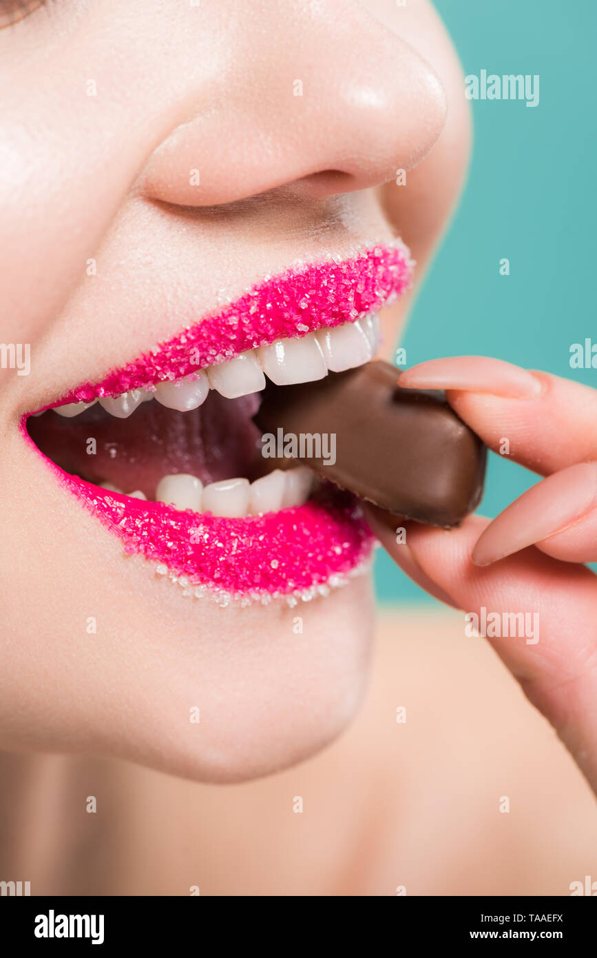 7/8-Ansicht von Frau Schokolade essen Süßigkeiten isoliert auf Blau Stockfoto