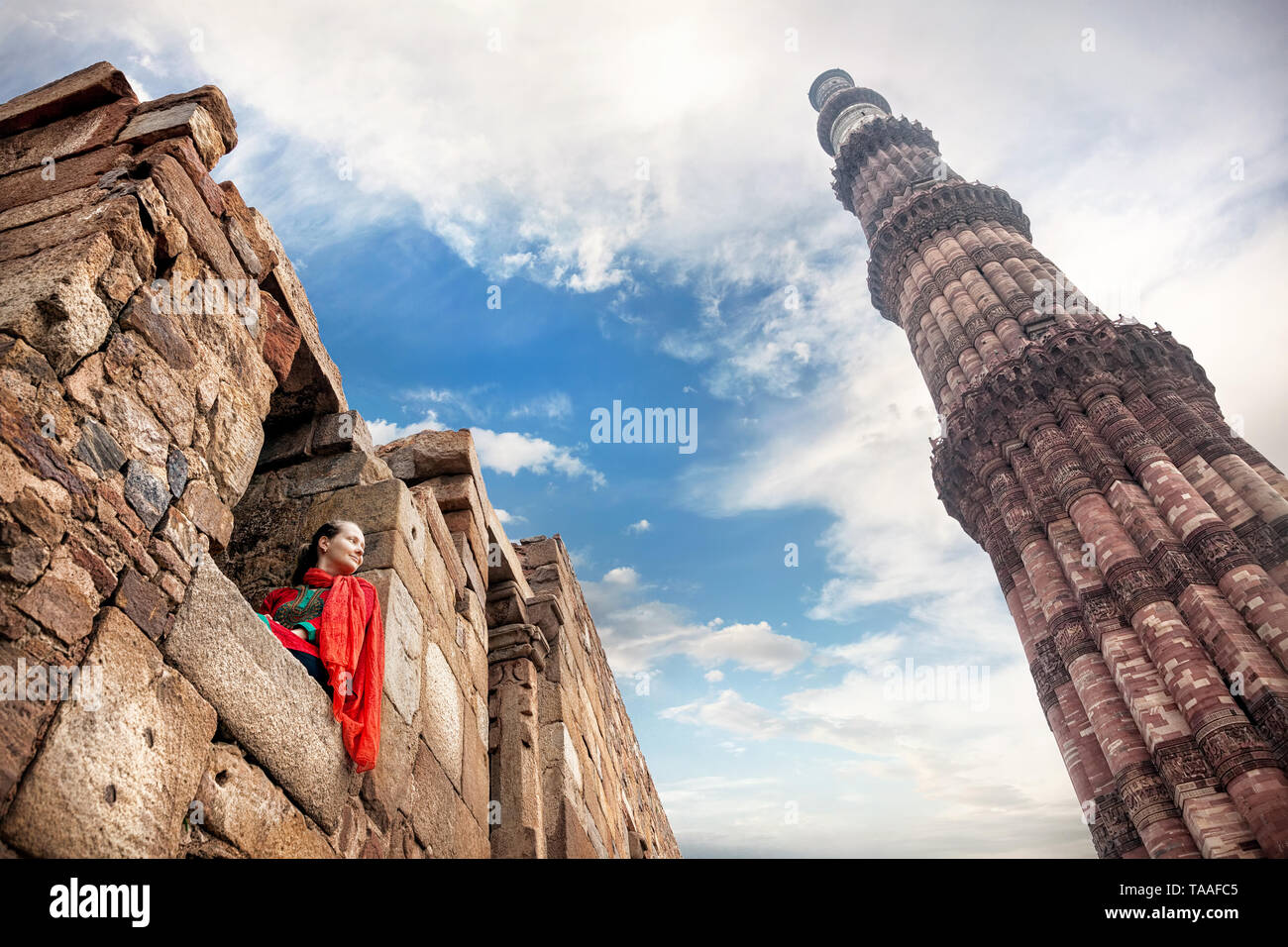 Frau in rot Kostüm saß im Fenster und Qutub Minar Turm in Old Delhi, Indien Stockfoto