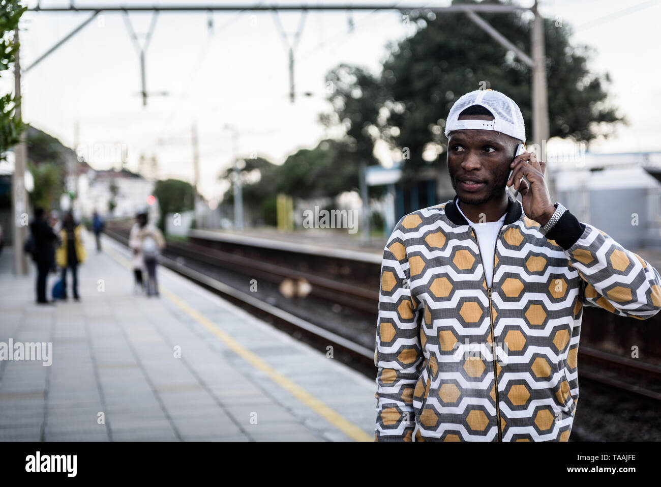 Ein Mann auf sein Handy im St James Bahnhof auf Südafrikas Kap Halbinsel, in der Nähe von Kapstadt Stockfoto