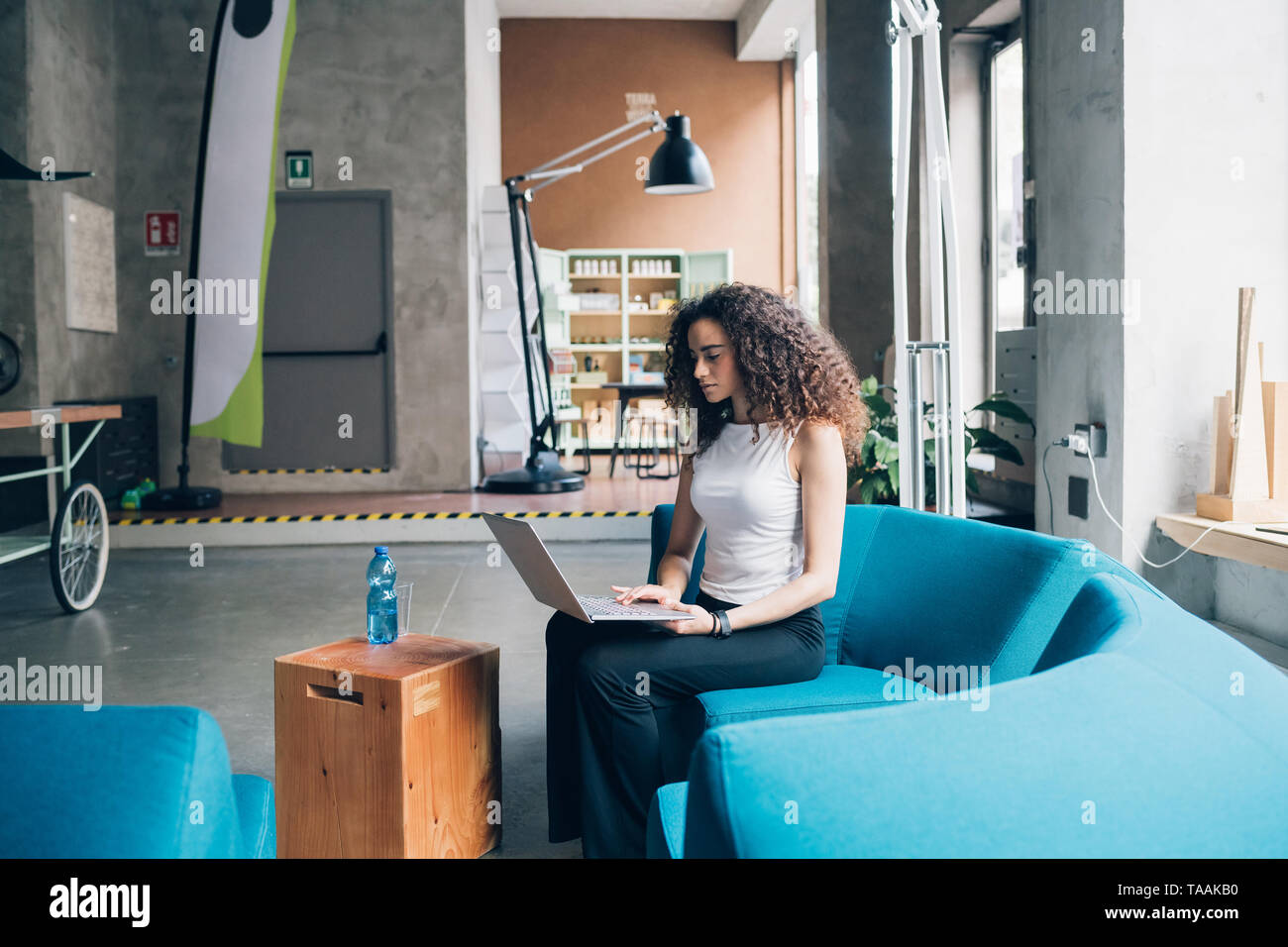 Junge Geschäftsfrau arbeiten und sitzen mit Laptop im modernen Büro - Interaktion, Kreativität, findige Stockfoto