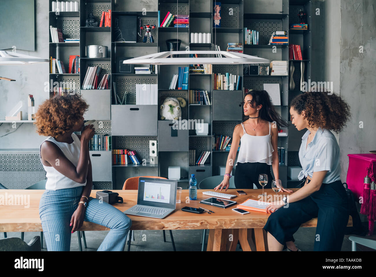 Drei junge Multirassischen Geschäftsfrauen in informellen Treffen in modernen Coworking office - Interaktion, Kreativität, findige Stockfoto