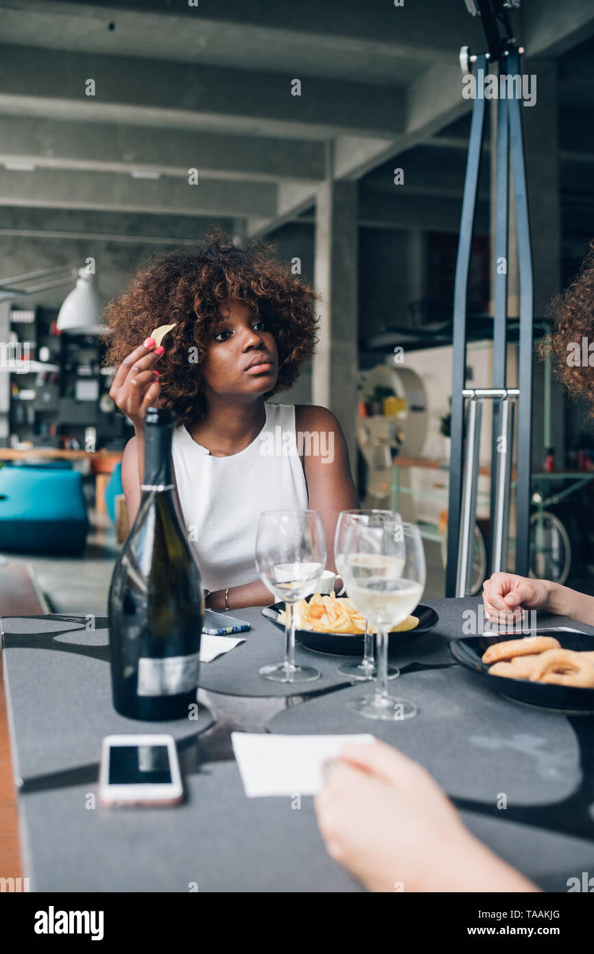 Junge afrikanische Frau trinkt Wein im modernen Restaurant mit Freunden - fröhlich, Jugendkultur, Freundschaft Stockfoto