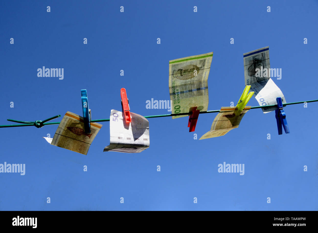 In Sonderborg, Dänemark - April 9, 2019: Banknoten, die auf eine reparierte Wäscheleine, mit einem blauen Himmel als Hintergrund, was darauf hindeutet, dass Geld waschen hat ta Stockfoto