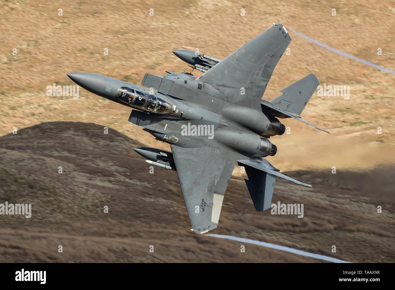 Ein USAF F-15 E Strike Eagle verlässt die Menai Bridge Exit in der Mach Loop in Wales, Großbritannien Stockfoto