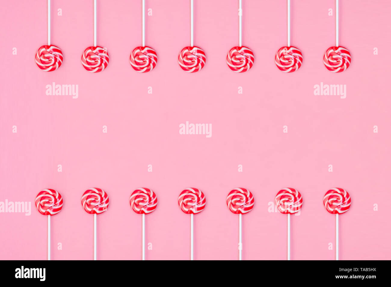 Viele bunte Lollipop candys in zwei Gruppe und leeren Raum in der Mitte auf rosa Hintergrund angeordnet. Flach Konzept. Stockfoto