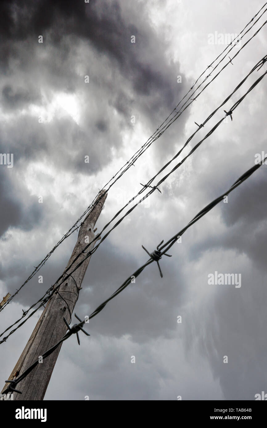 In der Nähe von Stacheldraht zaun & Holzzaun Post gegen bedeckt stürmischen Himmel; Ranch in Colorado, USA Stockfoto