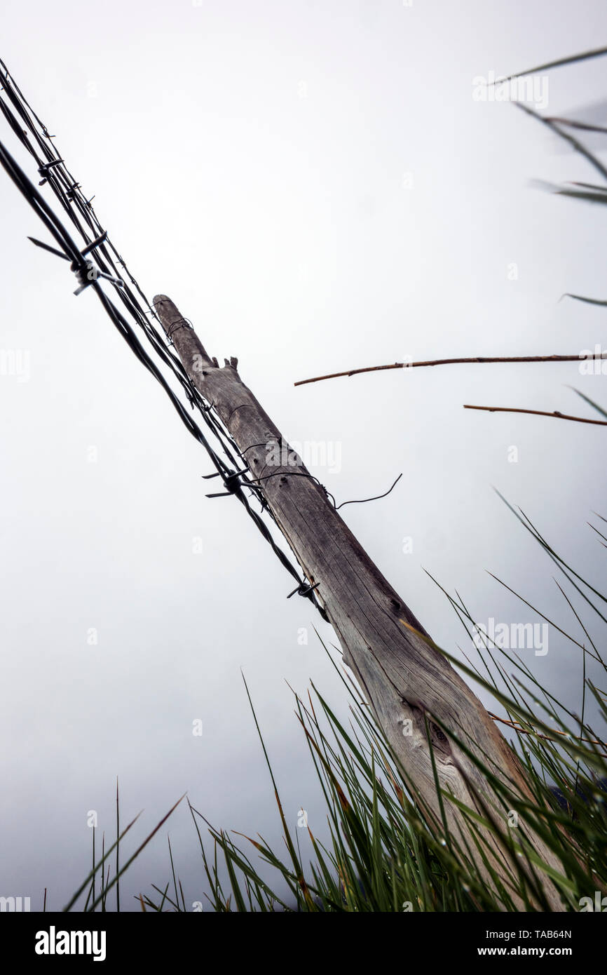 In der Nähe von Stacheldraht zaun & Holzzaun Post gegen bedeckt stürmischen Himmel; Ranch in Colorado, USA Stockfoto