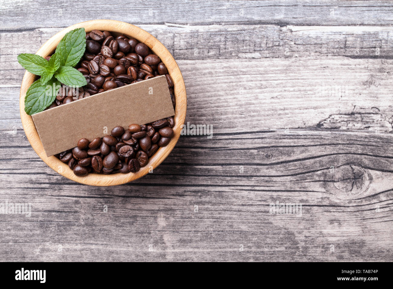 Kaffeebohnen in der Schüssel mit Papier Aufkleber auf Holz- Hintergrund Stockfoto