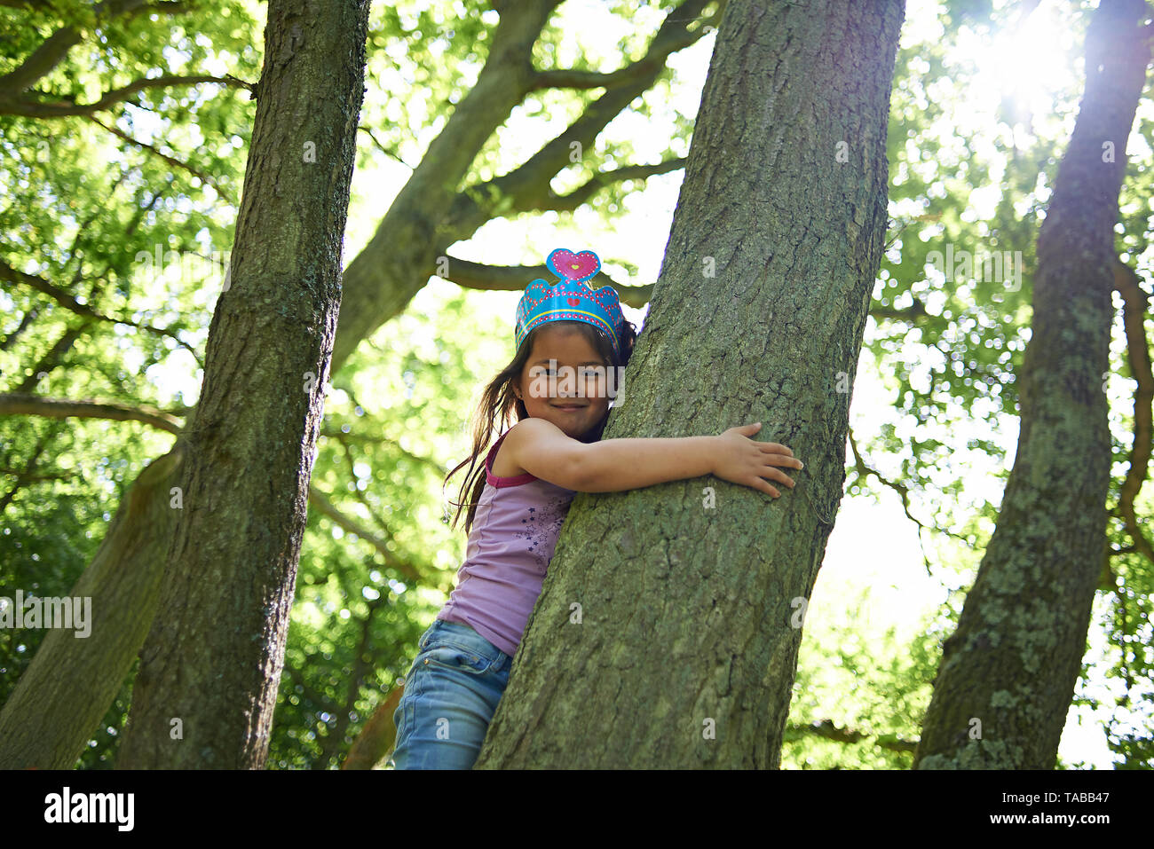 Nette junge Asiatin auf einen Baum und liebevoll umarmen den großen Stamm des Baums Stockfoto
