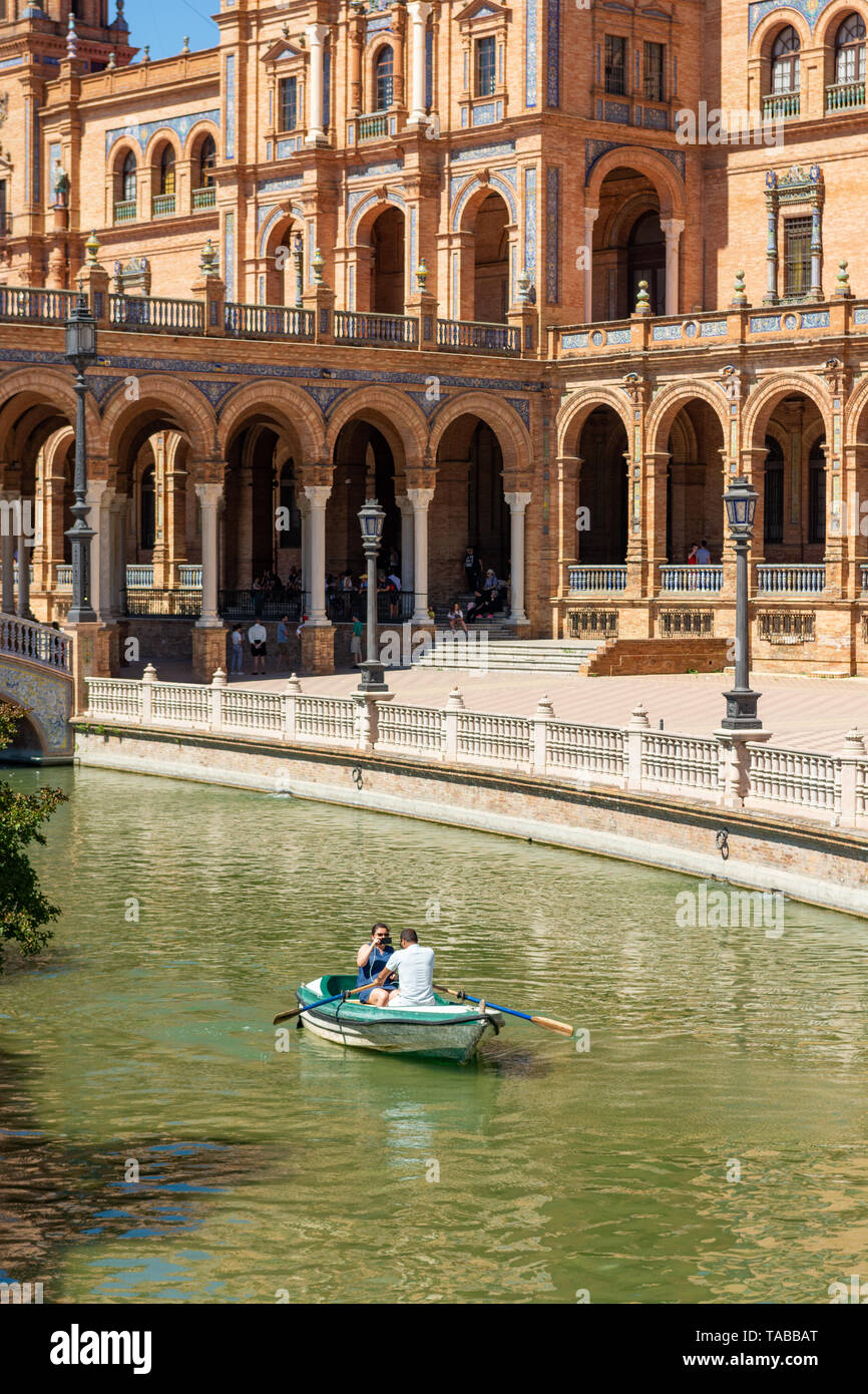 Paare, die in einem Ruderboot auf den See zum Bootfahren in der romantischen Umgebung der Plaza Espana, Sevilla, Region Andalusien, Spanien Stockfoto