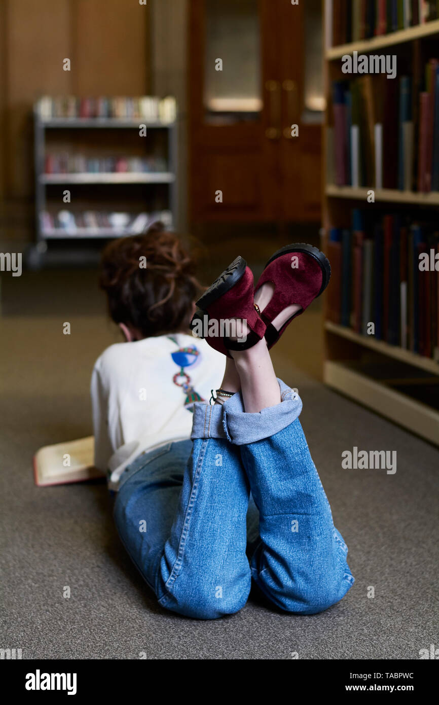 Studentin lesen Buch in einer öffentlichen Bibliothek Stockfoto