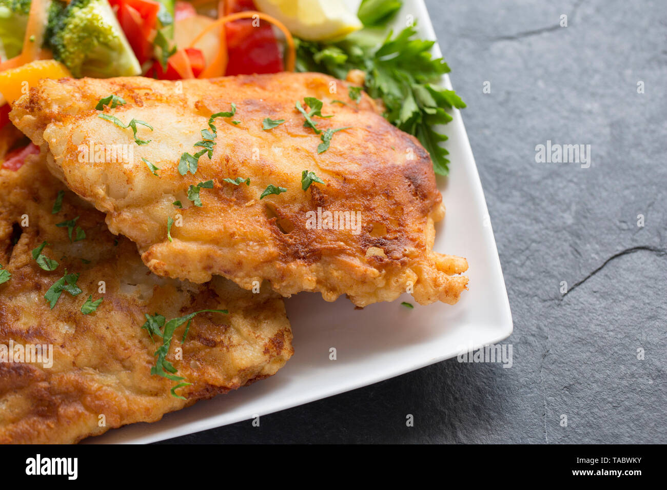 Zwei dicke Filets von Pollack Pollachius pollachius, dass tief in hausgemachter Teig gebraten und serviert mit Obst und rohem Gemüse. Die pollac Stockfoto