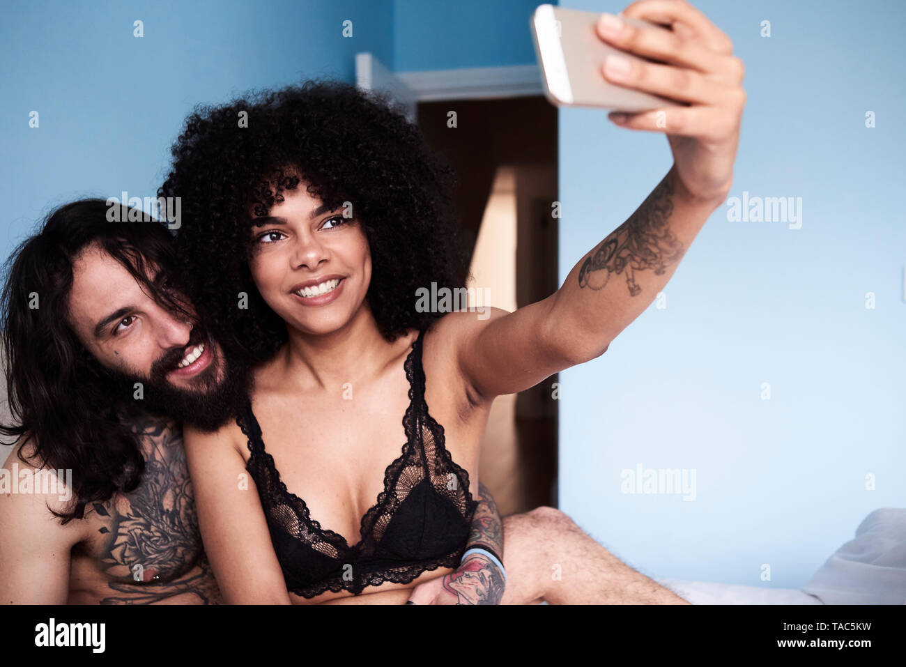 Gerne zärtlich junges Paar ein selfie im Bett Stockfoto