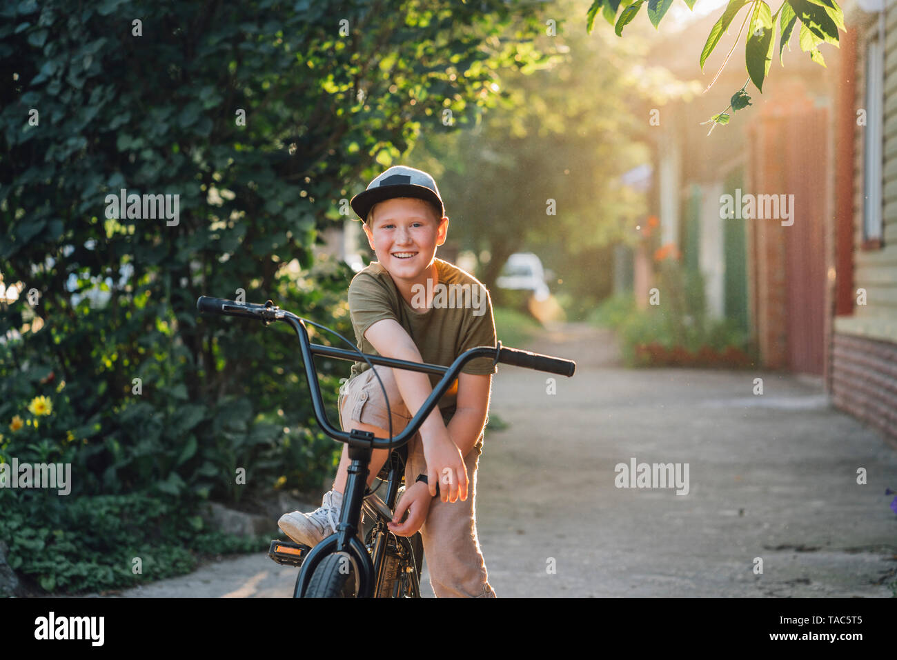 Portrait von lächelnden Jungen mit BMX-Bike auf der Straße Stockfoto