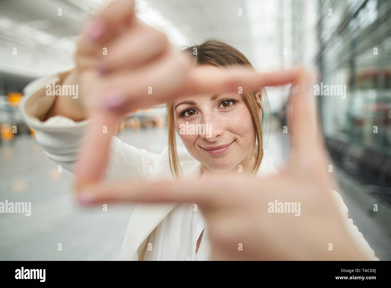 Portrait von lächelnden jungen Geschäftsfrau, finger Frame am Flughafen Stockfoto