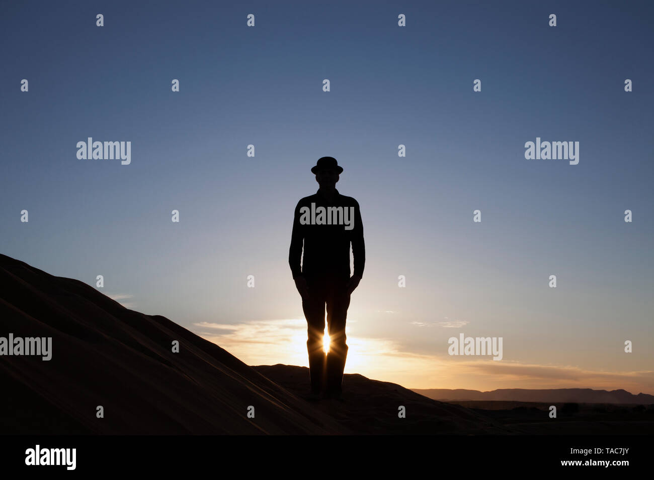 Marokko, Merzouga, Erg Chebbi, Silhouette der Mann, der eine Melone auf Wüste Düne bei Sonnenuntergang Stockfoto